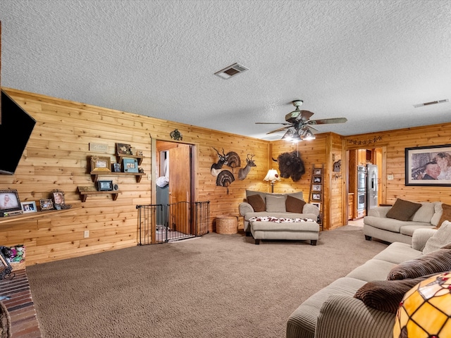 living room with wooden walls, carpet, a textured ceiling, and ceiling fan