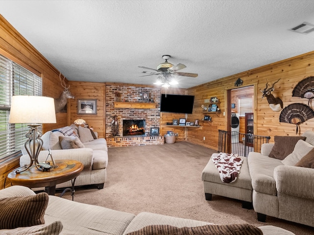 living room featuring ceiling fan, carpet floors, a textured ceiling, wooden walls, and a fireplace