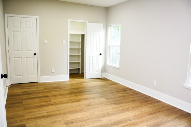 unfurnished bedroom featuring light hardwood / wood-style floors and a spacious closet