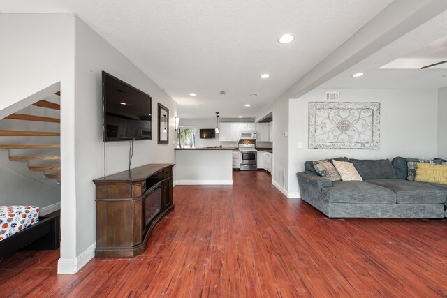 living area featuring baseboards, visible vents, dark wood-style floors, stairs, and recessed lighting