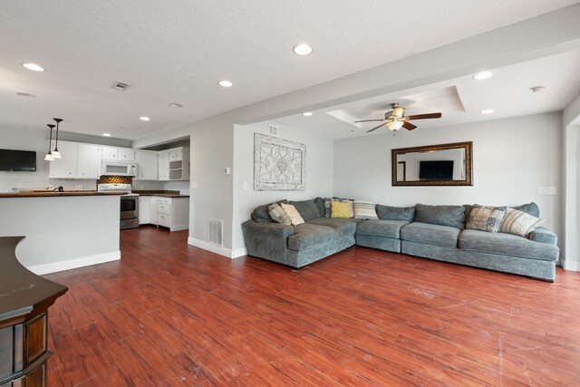 living area featuring baseboards, dark wood-style flooring, visible vents, and recessed lighting