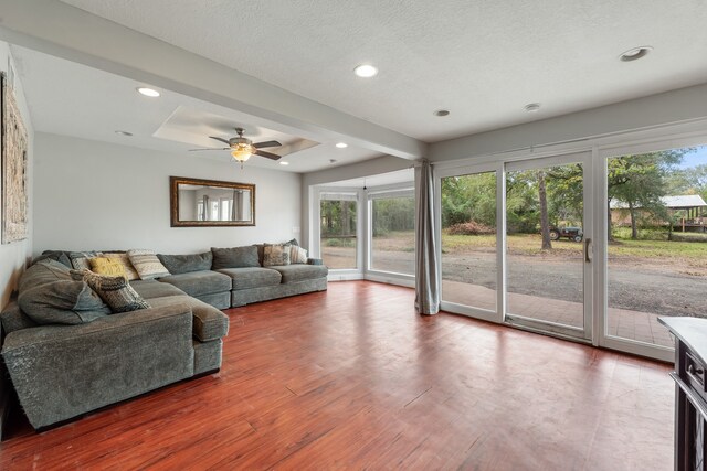 living room featuring a textured ceiling, a tray ceiling, wood finished floors, and recessed lighting