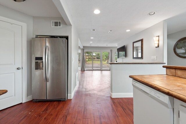 kitchen with recessed lighting, visible vents, dark wood-type flooring, stainless steel fridge, and dishwasher