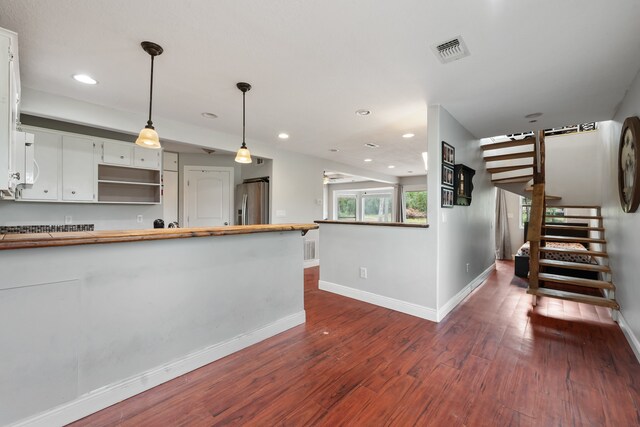 kitchen with stainless steel refrigerator with ice dispenser, open shelves, visible vents, white cabinets, and butcher block countertops