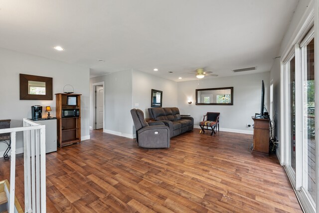 living area with baseboards, visible vents, and wood finished floors