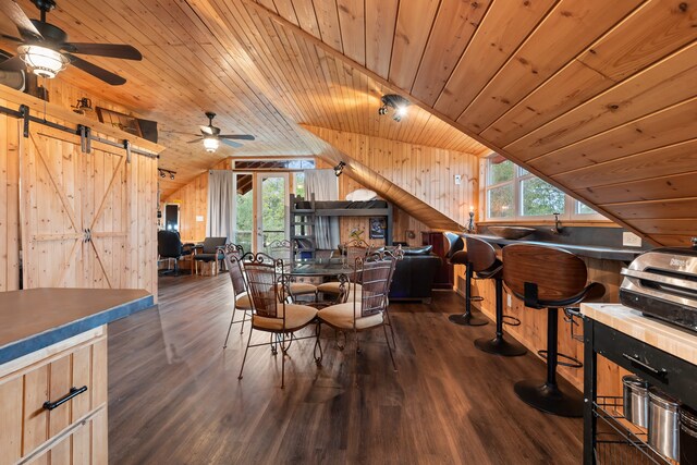 dining room with lofted ceiling, a barn door, wood ceiling, and dark wood-style flooring