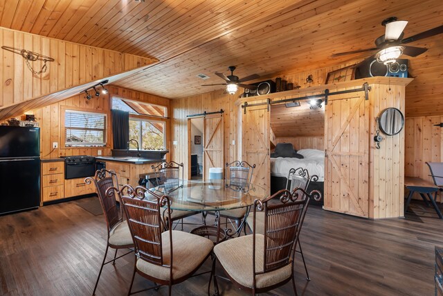 dining area featuring wood ceiling, a barn door, dark wood-style flooring, and a ceiling fan