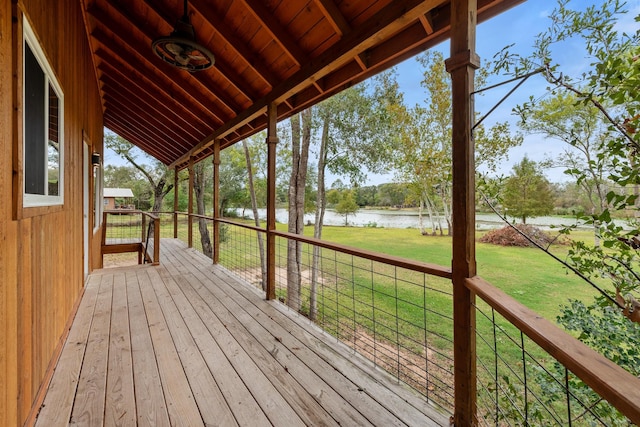 wooden terrace featuring a water view and a lawn