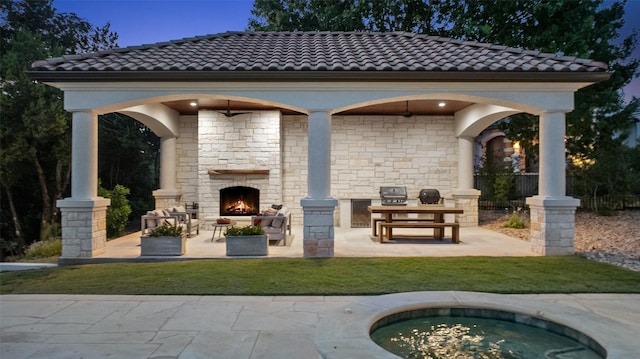 view of patio featuring an outdoor stone fireplace and area for grilling