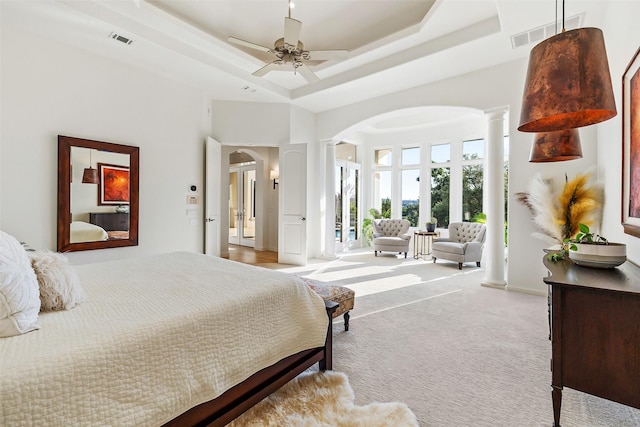 carpeted bedroom with a high ceiling, ceiling fan, a raised ceiling, and decorative columns