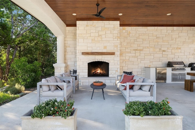 view of patio / terrace with ceiling fan, exterior kitchen, a grill, and an outdoor stone fireplace