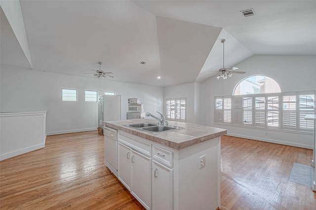 kitchen featuring a center island with sink, white cabinetry, sink, white appliances, and light hardwood / wood-style flooring