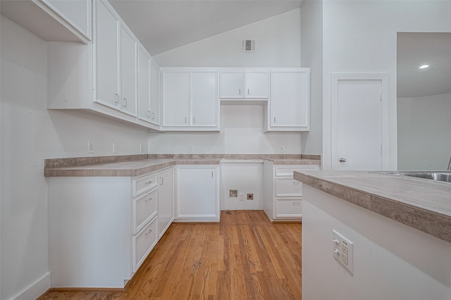 kitchen featuring white cabinets, lofted ceiling, and light hardwood / wood-style flooring