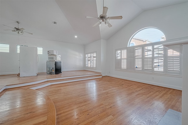 unfurnished living room featuring high vaulted ceiling, light hardwood / wood-style flooring, and ceiling fan