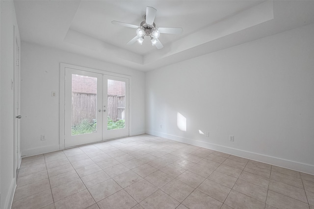 unfurnished room featuring a tray ceiling, french doors, light tile patterned floors, and ceiling fan