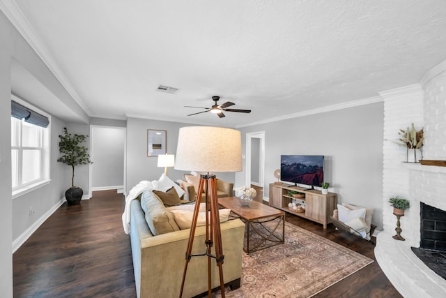 living room featuring a brick fireplace, ceiling fan, dark hardwood / wood-style floors, and crown molding