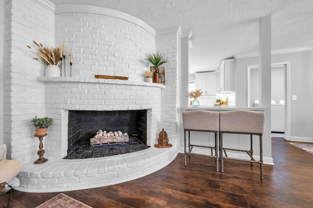 living room featuring dark hardwood / wood-style flooring, a textured ceiling, crown molding, and a fireplace