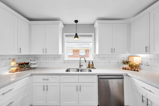 kitchen featuring stainless steel dishwasher, white cabinetry, sink, and tasteful backsplash