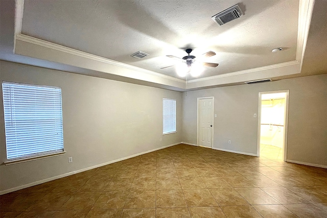 empty room with ceiling fan, crown molding, a tray ceiling, and light tile patterned floors