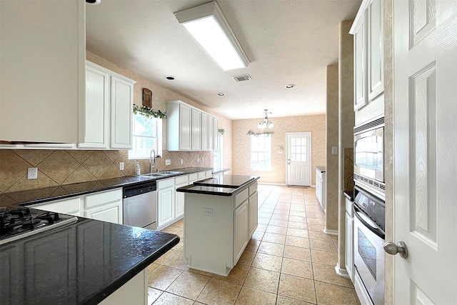 kitchen with white cabinetry, appliances with stainless steel finishes, sink, and a center island