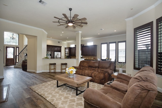 living room with crown molding, ceiling fan with notable chandelier, and dark hardwood / wood-style floors