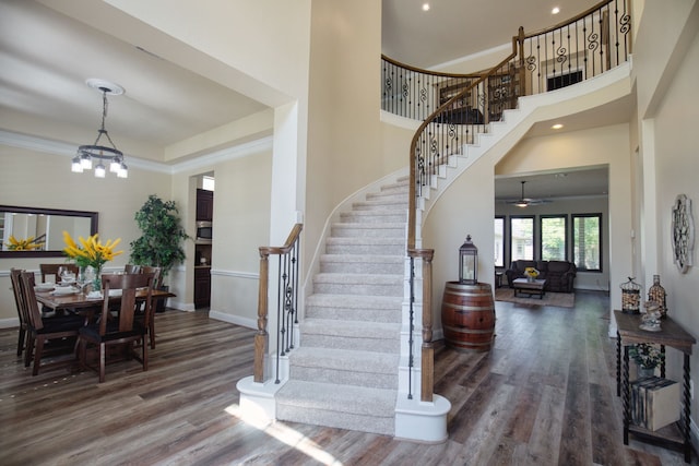 entrance foyer with ceiling fan with notable chandelier, dark wood-type flooring, and a high ceiling