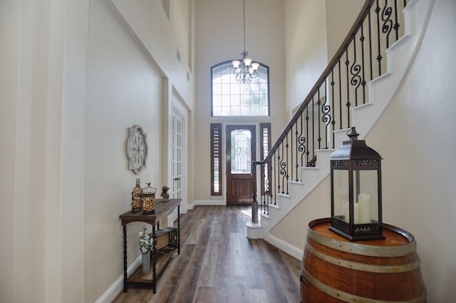 foyer with a chandelier, a towering ceiling, and dark hardwood / wood-style floors