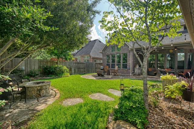 view of yard featuring a patio, ceiling fan, and an outdoor living space with a fire pit