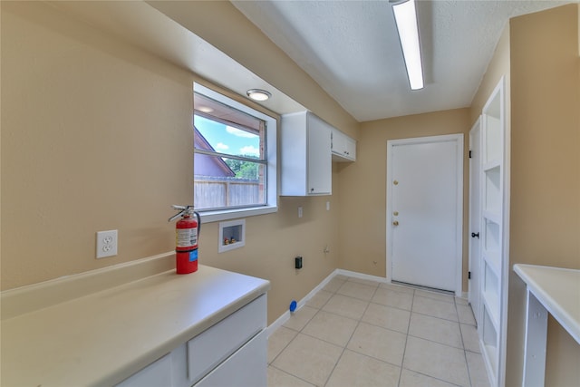 laundry room featuring cabinets, a textured ceiling, hookup for a washing machine, and light tile patterned floors