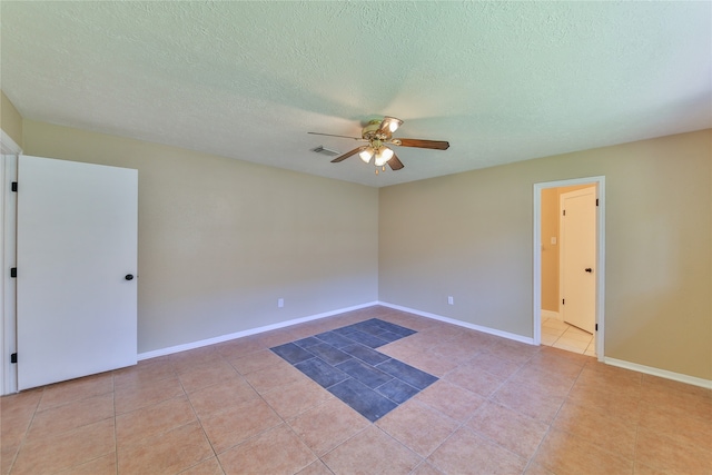 spare room with a textured ceiling, ceiling fan, and light tile patterned floors