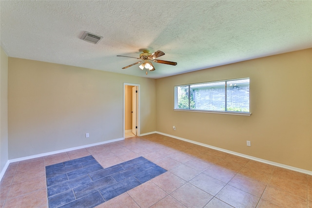 spare room with a textured ceiling, light tile patterned floors, and ceiling fan