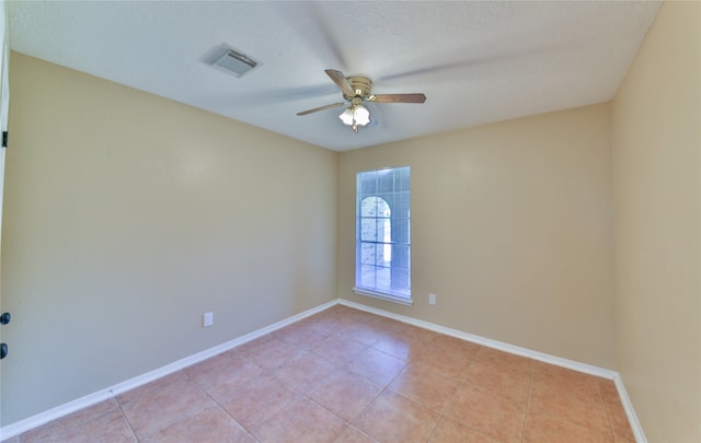 tiled empty room featuring ceiling fan