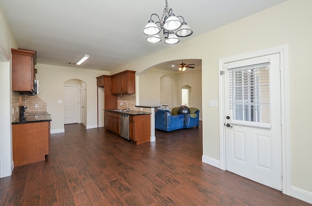 kitchen with dishwasher, sink, dark wood-type flooring, backsplash, and ceiling fan with notable chandelier