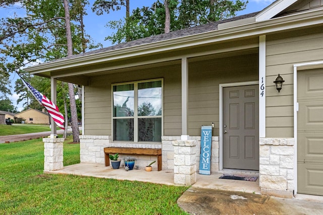 doorway to property with covered porch, a garage, and a lawn