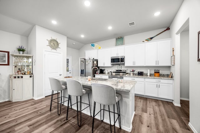 kitchen with stainless steel appliances, white cabinets, hardwood / wood-style floors, sink, and an island with sink