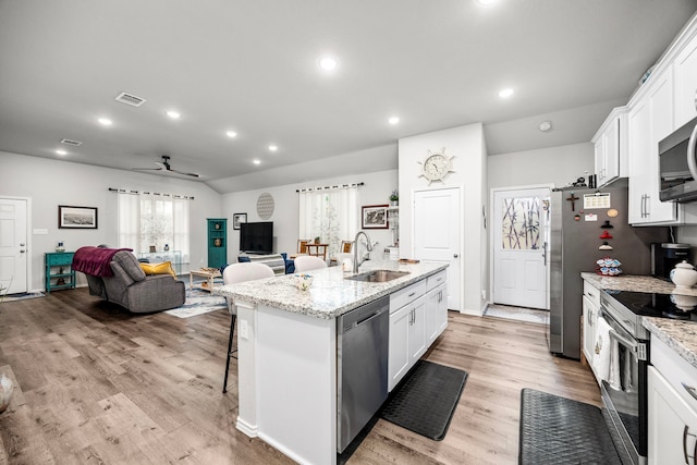 kitchen with white cabinets, sink, an island with sink, light wood-type flooring, and appliances with stainless steel finishes