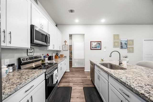 kitchen featuring light hardwood / wood-style flooring, sink, light stone countertops, white cabinetry, and appliances with stainless steel finishes