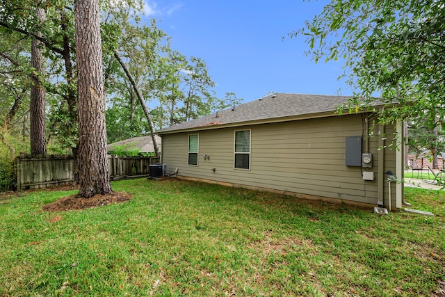 rear view of house with central AC and a yard