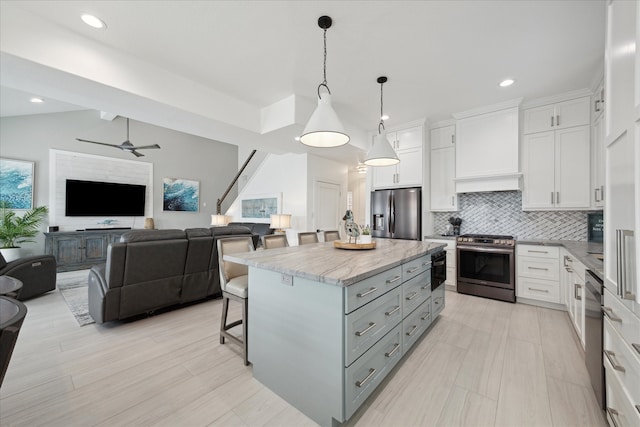 kitchen with a center island, white cabinets, stainless steel appliances, and vaulted ceiling