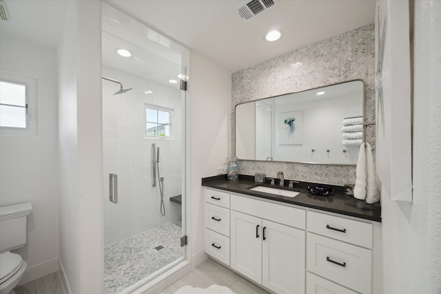 bathroom featuring vanity, toilet, and a shower with door