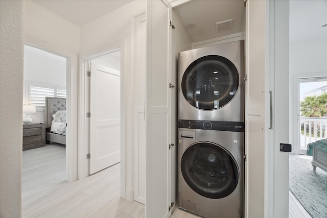 laundry room featuring stacked washer / dryer and light hardwood / wood-style floors