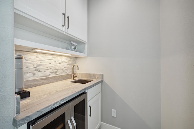 bar with decorative backsplash, white cabinets, wine cooler, and sink