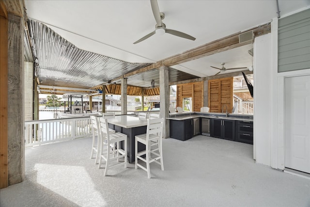 view of patio / terrace featuring an outdoor kitchen, ceiling fan, and a wet bar