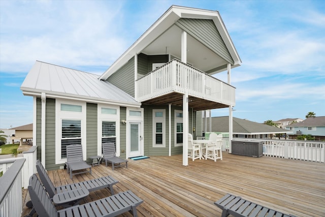 rear view of property featuring a balcony and a wooden deck