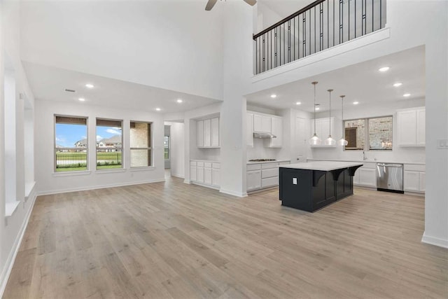 kitchen with white cabinetry, a kitchen island, decorative light fixtures, and appliances with stainless steel finishes