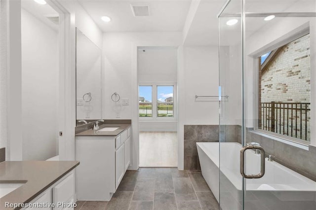 bathroom featuring vanity, tile patterned flooring, and a relaxing tiled tub