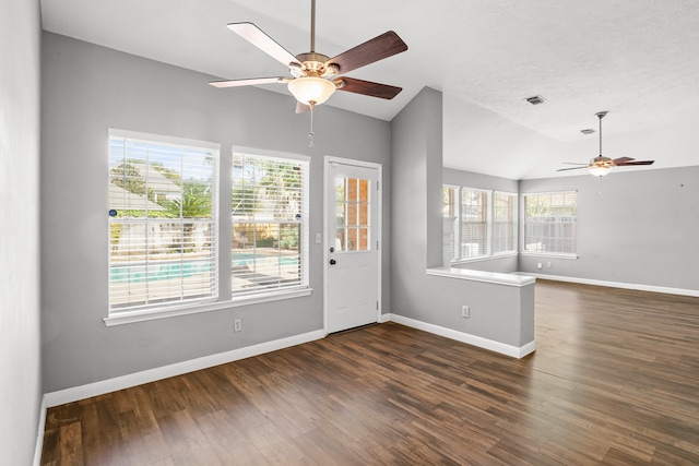 spare room with dark wood-type flooring, a healthy amount of sunlight, ceiling fan, and vaulted ceiling