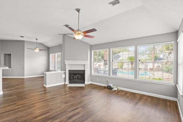 unfurnished living room featuring ceiling fan, dark hardwood / wood-style floors, a tiled fireplace, and vaulted ceiling