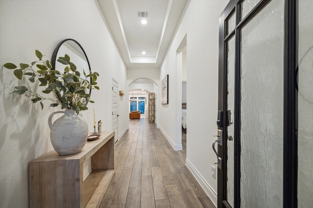 hallway with hardwood / wood-style flooring and a tray ceiling