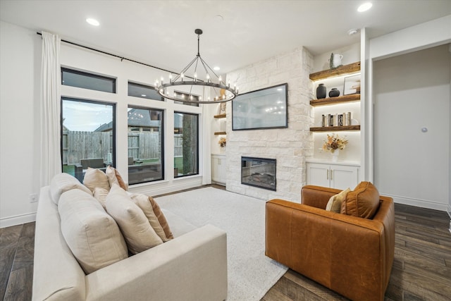 living room with dark hardwood / wood-style flooring, a stone fireplace, and a notable chandelier